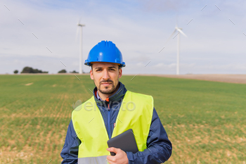 turbine farm using his digital tablet. Worker looking at the camera in the facilities of renewable and non-polluting electrical energy.