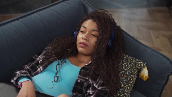 Relaxed Woman in Headphones Listening To Music on Couch