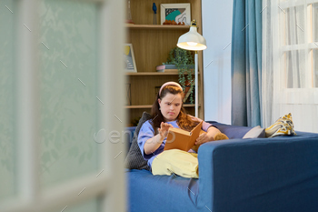 Young serious woman with Down syndrome turning page of book