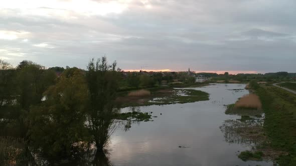 Rising up drone flyover rural small village by flooded river at sunset