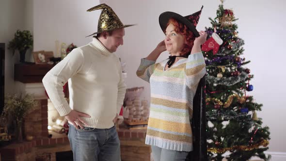 Middle Shot Portrait of Smiling Positive Caucasian Woman Boasting Christmas Costume To Man at Home