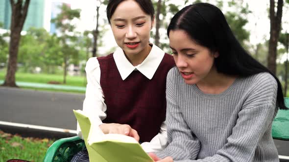 Two Young Female Friends Talking and Discussing with Each Other in Public Park Outdoors