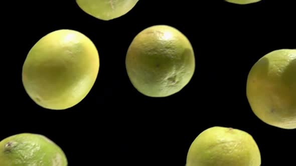 Closeup of the Ripe Green Limes Falling Down on the Black Background