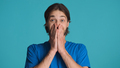 Excited man covering mouth hands looking happy over blue background. Speechless expression - PhotoDune Item for Sale