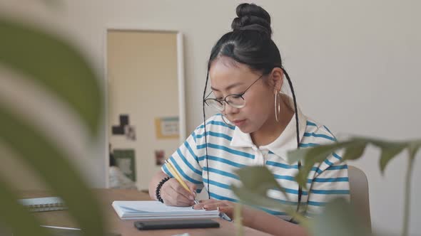 Asian Teenage Girl Doing Homework and Using Her Smartphone