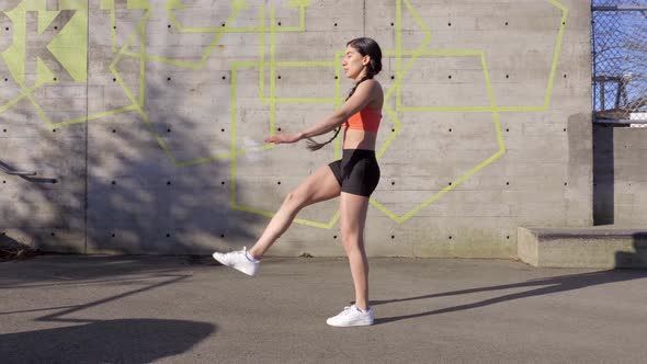 Young woman does high kick with extended arm exercise routine, Profile Wide Shot