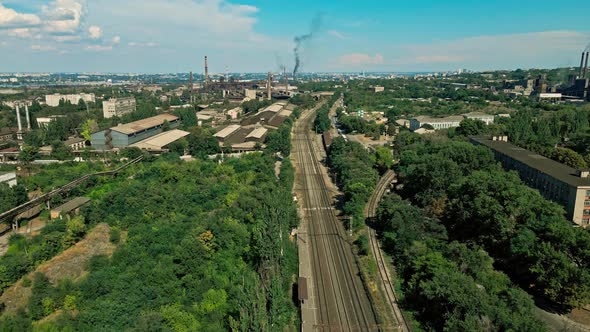 Railway To the Plant in the Industrial Area of the City Near a Residential Area with Green Trees.