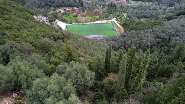 Moving in shot of Soccer field within green mountains. Revealing Shot of scenic mountain range in th