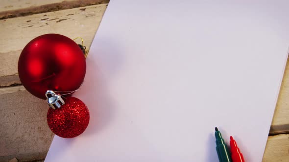 Christmas bauble, felt pen and paper on wooden plank