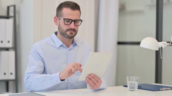 Middle Aged Man Using Tablet at Work