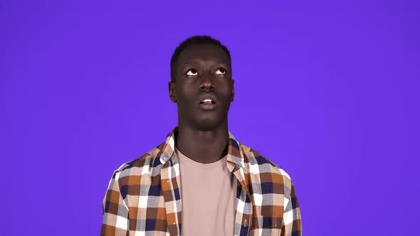 Portrait of Darkskinned Young Man Rolling His Eyes Up Isolated on Blue Background