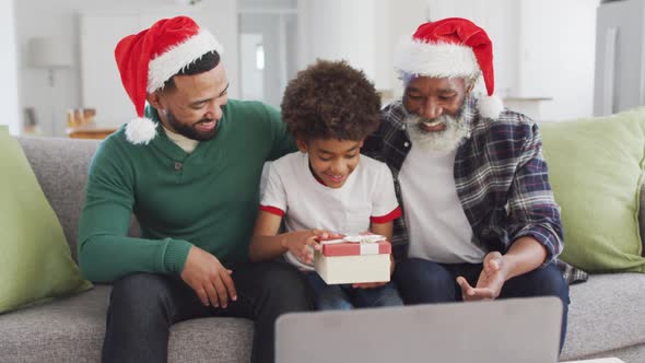 Father son and grandfather opening gift box while having video chat on laptop