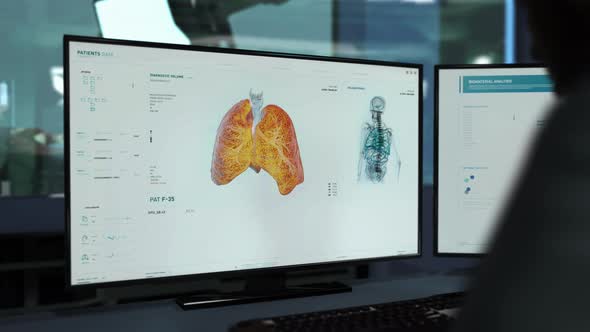 A Doctor is Sitting behind the desk and controlling Analysis of the Human Body alt