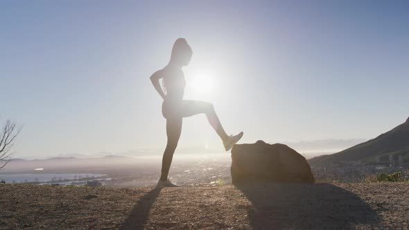 African american woman exercising outdoors stretching legs in countryside at sunset