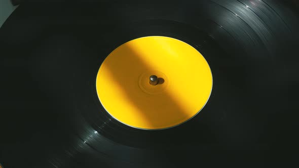 Black Vinyl Retro Record Rotating Plate with Yellow Label on Old DJ Turntable Player