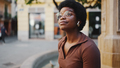 Cute Afro American woman in glasses sitting on the street listen - PhotoDune Item for Sale