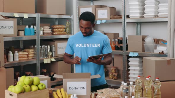 African American Man Using Tablet at Donation Storage