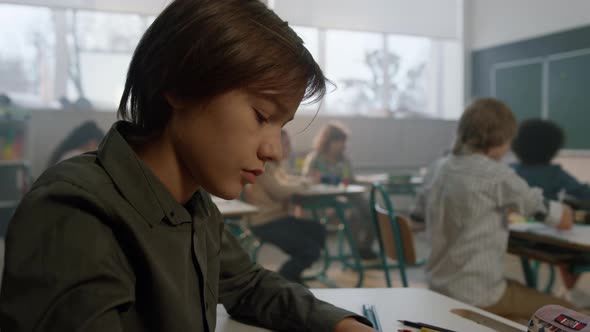 Student Sitting at Desk in Classroom During Lesson