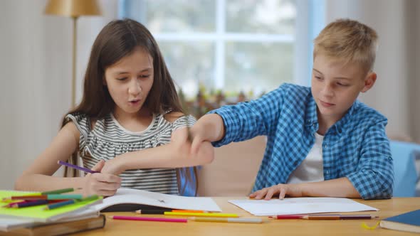 School Boy and Girl Sitting at Table and Drawing on Each Other Paper with Colorful Pencils