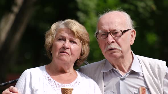 Happy old couple eating ice cream in the park.