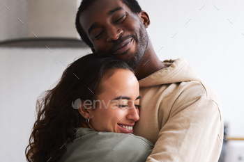 Loving Young Couple Hugging At Home Standing In Kitchen Together