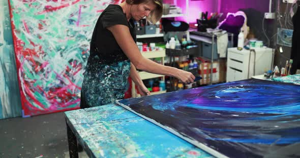 Senior woman painting inside her atelier studio at home