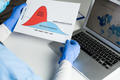 Doctor wearing protective gloves holding Flatten the Curve chart - PhotoDune Item for Sale