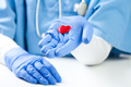 Female doctor holding small red heart on palm of hand - PhotoDune Item for Sale
