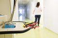 Medical equipment in a hospital corridor with an out of focus nurse walking down the hallway - PhotoDune Item for Sale