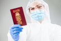 Medical healthcare worker in full personal protective equipment holding red passport - PhotoDune Item for Sale