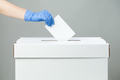 Caucasian female hand wearing blue protective latex rubber glove placing ballot paper in vote box - PhotoDune Item for Sale