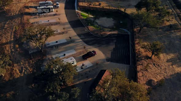 Aerial view rotating and pulling back of an RV trailer in an RV park at sunset.