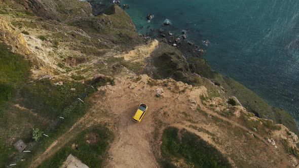 A Yellow Car Stands on the Edge of a Cliff at Cape Lermontov