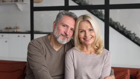 Serene and Carefree Middleaged Couple in Love Looks at the Camera and Smiles