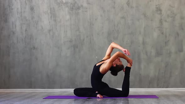 Woman Sports Clothes is Engaged in Yoga on a Purple Sports Mat Studio with Natural Consecration