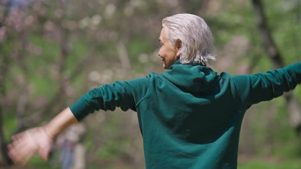 Back View of Senior Greyhaired Woman Stretching Hands Behind Back