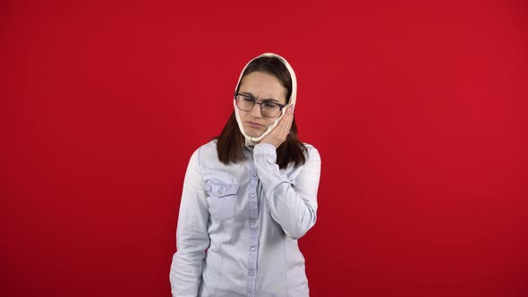 A Young Woman with Glasses Has a Rewound Head Due To a Pain in a Tooth