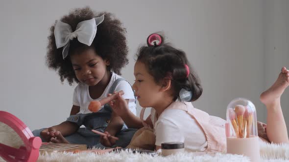 2 kids playing with cosmetics on bed