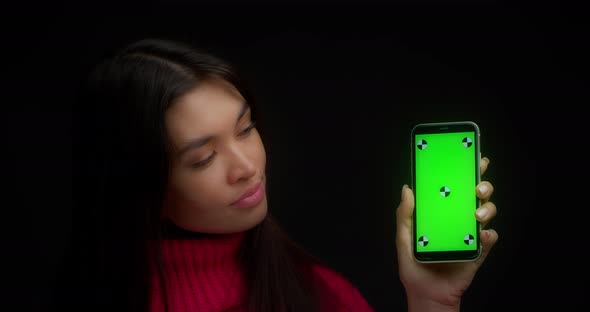 Woman in a Pink Sweater Shows Vertical Green Phone Screen for Copying