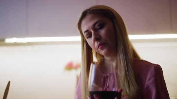 Thoughtful Woman Looks at Red Wine Before Degustation