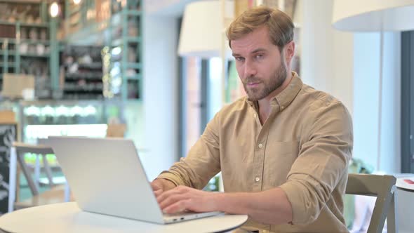 No Finger Gesture By Young Man with Laptop in Cafe