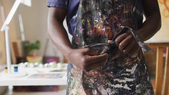 African american male painter tying his apron in artist studio