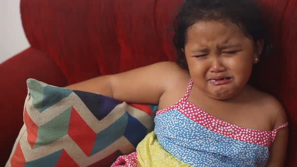 Cute asian little girl eating while crying at home and almost choked