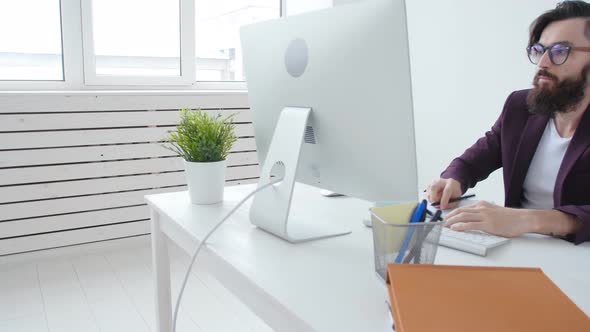 Concept of Office Work or Freelancing. Young Bearded Stylish Man Working at the Computer