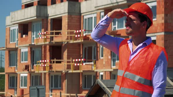 Construction Worker Thinks About Something in Front of Building Site