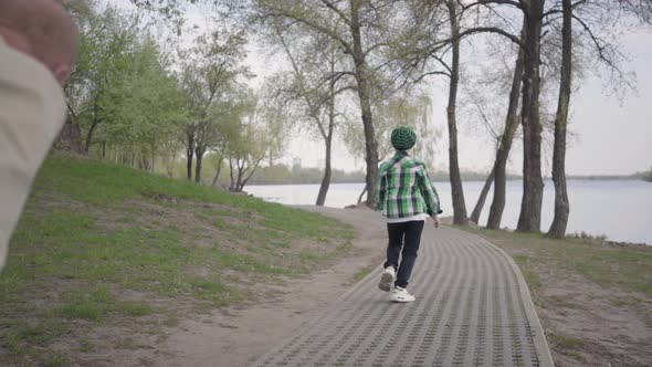 Little Boy Running From His Grandfather in the Park