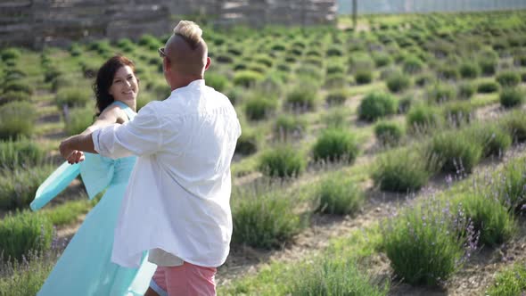 Joyful Adult Couple Spinning in Slow Motion Dating on Lavender Field on Summer Day