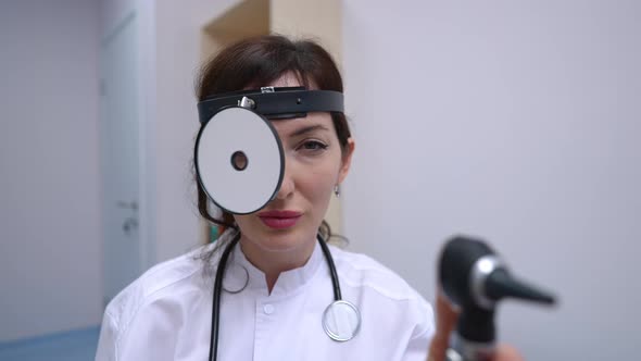 Portrait of Positive Caucasian Female Otolaryngologist Posing in Slow Motion with Medical Equipment