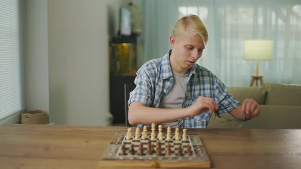 Young Man Wearing Glasses Plays Chess Alone With Himself At Home