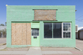 Abandoned roadside store in a small town, boarded up window, green painted exterior. - PhotoDune Item for Sale